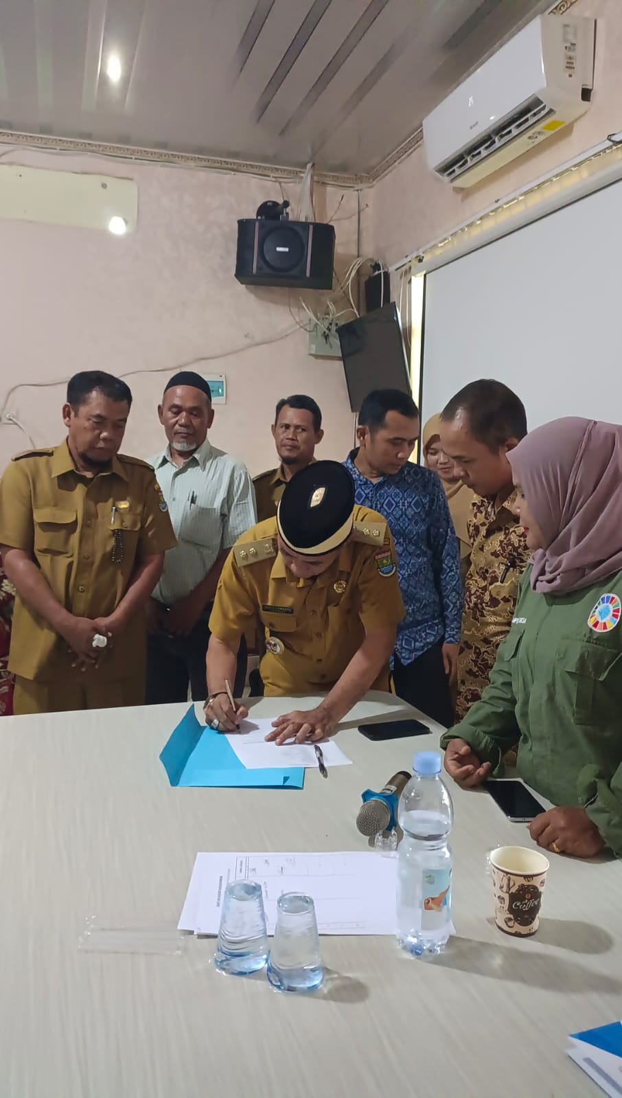 "Kepala Desa Rajeg menandatangani dokumen pembentukan Kopdesus Merah Putih dalam Musyawarah Desa Khusus, disaksikan oleh perangkat desa dan perwakilan masyarakat di kantor Desa Rajeg."