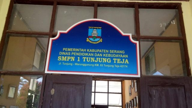 Plang nama SMPN 1 Tunjung Teja, Kabupaten Serang, yang menjadi sorotan terkait dugaan pungutan liar sebesar Rp500.000 per siswa untuk keperluan kelulusan.