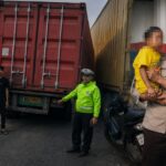 Aipda Cawa Daeng mengevakuasi anak korban yang selamat dalam kecelakaan maut antara sepeda motor dan truk trailer di kawasan Cilincing, Jakarta Utara, Minggu (21/6/2026).